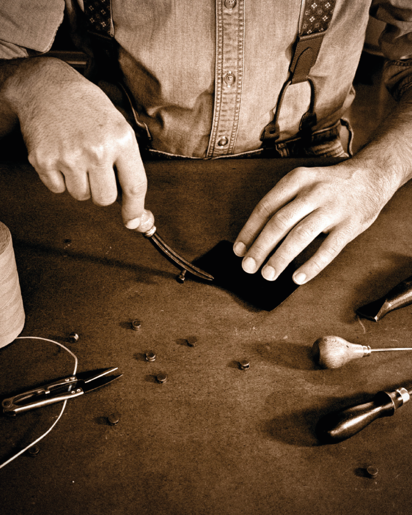 Mani di un artigiano durante la realizzazione artigianale di un accessorio
